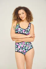 Conjunto de bikini estampado con flores y hojas en tonos celeste, turquesa, rosa y violeta. El corpiño es deportivo con breteles negros y la bombacha es de tiro alto con ribete negro.