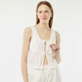 Blusa blanca sin mangas con bordado inglés, escote en V y lazos ajustables en el frente.