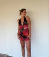 Minivestido con estampado floral en tonos rojos y negros, con escote halter de encaje negro.