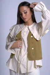 Chaleco tejido color crema con escote en V y cierre frontal con lazos. Presenta bordados de flores en tonos naranja, verde y blanco.