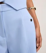 Short de sastre color marrón, de cintura alta, con bolsillos laterales decorados con tachuelas metalizadas y recortes delanteros.