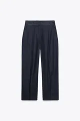 Pantalón azul marino de corte recto, confeccionado en lino. Presenta tiro alto, pinzas delanteras, bolsillos laterales y falsos bolsillos de vivo en la parte trasera.