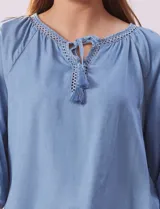 Blusa celeste de tencel, marca Marissa Olivia, con cuello a la base, escote en V con aplique de cordel y lazo de ajuste. Manga larga amplia con puño elastizado.