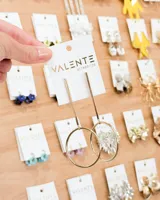 Caravanas colgantes doradas, compuestas por una barra delgada vertical que conecta con un aro grande.