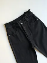 Pantalón de jean negro, de corte semioxford, con cintura alta y botón plateado.