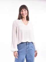 Blusa blanca de mangas largas con puños elásticos y escote en V con detalle de volantes.