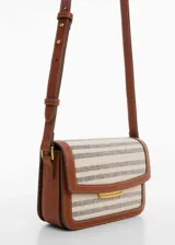 Bandolera rectangular de tela rayada en tonos beige y gris, con detalles en cuero marrón. Tiene correa larga ajustable, cierre con solapa y botón imantado, y herrajes dorados.