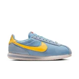 Championes Nike Cortez celestes con detalles en amarillo y suela blanca.
