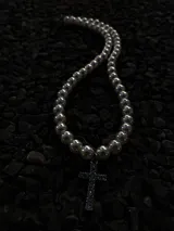 Collar de perlas blancas con dije de cruz plateada con incrustaciones de strass.