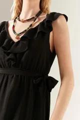 Vestido midi negro con cuello en V y volados en el escote y el ruedo.