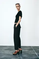 Pantalón tobillero negro con cintura elástica ajustable con cordones, bolsillos delanteros y falsos bolsillos con solapa en la espalda.