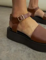 Sandalias de cuero color marrón con plataforma negra.