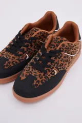 Zapatillas bajas de cuero sintético con estampado animal print, puntera y cordones negros, suela color caramelo y detalle en el talón color blanco.