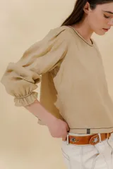 Blusa color beige de lino 100% con mangas balloon y detalle de tablón en el hombro. Tiene mangas largas con detalle de 2 pespuntes elásticos en contratono, el recurso del elástico es ideal para remangarse la manga generar más volumen. Calce recto, largo por arriba de la cadera.