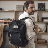 Mochila negra de tela Oxford con base de nobuk color marrón, dos bolsillos frontales con cierre y tiradores de cuero. Correas de hombro acolchadas.
