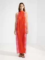 Vestido largo color naranja con estampado de flores rosas, corte recto, cuello halter y espalda descubierta.