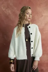 Cardigan tejido color crudo, con mangas abullonadas y botones negros.