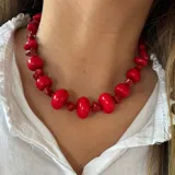Collar corto de cuentas rojas de diferentes tamaños y formas, con cierre ajustable.
