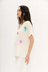 Remera color crudo de corte holgado con mangas cortas rebatidas y bordados de motivos egipcios en hilo de colores.