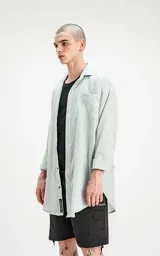 Camisa celeste de manga larga con bolsillo ojal en delantero, cartera escondida y calce oversize.
