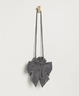 Bolso de mano tipo saco o pochette, confeccionado en terciopelo gris oscuro, con cierre fruncido y un gran lazo decorativo frontal. Posee una correa fina para llevar al hombro o cruzado.