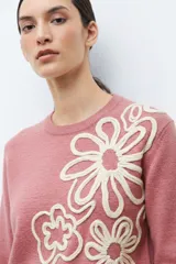 Sweater color rosado melange con cuello redondo y manga larga. Presenta un bordado abstracto en color crema en la parte frontal.