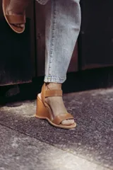 Sandalias de cuero color marrón con plataforma de cuña y tira con hebilla al tobillo.