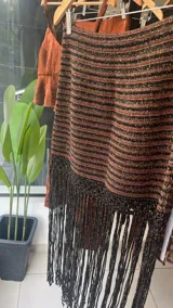 Falda tejida a mano en crochet, color crudo, con flecos en el ruedo y abertura lateral.