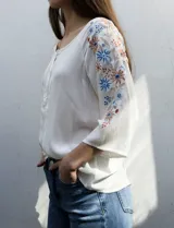 Blusa azul con escote redondo, mangas 3/4 con bordado floral y abertura central con botones. Marca Forgotten Grace.