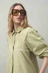 Camisa blanca de mangas 3/4 abullonadas con bordado floral en el frente.