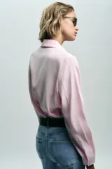 Camisa rosa de cuello solapa y manga larga. Tejido suave. Cierre frontal con botones a tono.