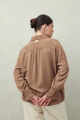 Camisa negra de manga larga con cuello clásico y botones frontales. El tejido presenta una textura arrugada o plisada, y los puños tienen un detalle fruncido o elástico.