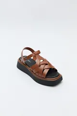 Sandalia negra con plataforma bicolor y capellada de tiras entrelazadas con textura símil reptil. Tiene hebilla metálica lateral para ajustar el calce y suela de goma.