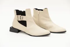 Botín de cuero rojo con elásticos laterales negros, aplique de hebilla metálica y taco cuadrado bajo. Cierre con cremallera lateral.