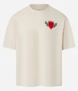 Remera color crema de corte boxy, con cuello redondo y mangas cortas. Presenta un estampado de automovilismo con un escudo rojo, una letra "D" estilizada y banderas a cuadros.