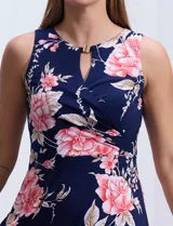Vestido largo de seda fría con estampado floral en tonos rosados y blancos sobre fondo azul marino. Presenta cuello redondo con abertura en forma de ojal y aplique metálico.