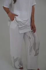 Pantalón de lino blanco con estampado abstracto en gris en la parte inferior de las piernas.