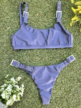 Conjunto de bikini azul con corpiño de breteles finos y hebillas metálicas en los tirantes. La bombacha es colaless y también tiene hebillas metálicas en los laterales.
