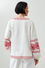 Blusa blanca de lino con bordados rojos en cuello, mangas y ruedo, de corte holgado y manga larga.