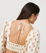 Blusa cropped de lino con escote corazón, lazada en la espalda, manga larga abullonada y estampado de anacardos.