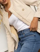 Chaqueta de tweed color beige, marca Nanette. Tiene cuello a la base, abertura central, bolsillos delanteros, puños con botones perlados, terminación desflecada y forro interno.