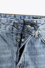 Pantalón de jean celeste de tiro bajo, corte flare, cropped y cinco bolsillos.