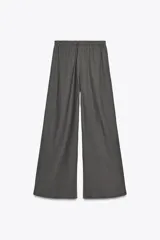 Pantalón blanco de lino, de corte ancho y tiro medio, con cintura elástica ajustable con cordones y bolsillos laterales.