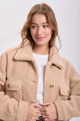Sobrecamisa color beige de textura sherpa, con cuello clásico, cierre frontal con botones a tono, bolsillos de parche con solapa en el pecho y corte recto.