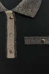 Chomba negra de corte slim fit, con cuello polo y mangas cortas. Presenta un falso bolsillo en el pecho y cierre frontal con botones. Detalle de hilo metalizado en cuello, bolsillo y tapeta.