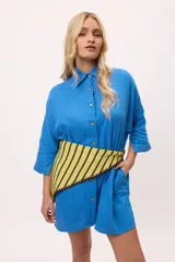 Vestido camisero a rayas verticales de colores pastel, con cuello camisero, cierre frontal con botones y mangas largas.