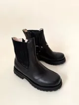 Botín negro de cuero vacuno con elásticos laterales y estribo desmontable con apliques y herrajes metálicos color níquel.