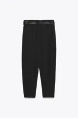 Pantalón negro de tiro alto con cintura elástica en la parte trasera y cinturón. Tiene bolsillos delanteros y falsos bolsillos de ojal en la parte trasera. El bajo está acabado con pinzas delanteras. El cierre frontal es con cremallera, botón interior y gancho.