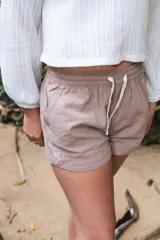 Short color beige con cintura elástica ajustable con cordón, bolsillos laterales y logo estampado en la pierna izquierda.