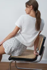Conjunto de pijama corto blanco, compuesto por una remera de algodón con estampado de texto en el pecho y un short con estampado de corazones.